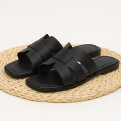 Schwarze Damenslipper aus Kunstleder – flache Sommerschuhe mit breiten Riemen und offenem Zehenbereich, minimalistisch und bequem für Alltag und Urlaub.